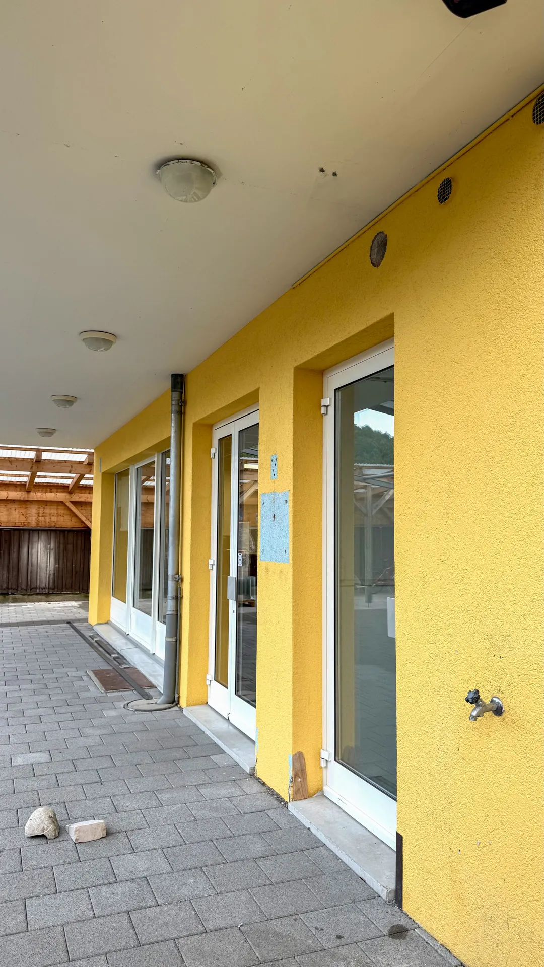 Leerer Raum mit dunkelblauen Wänden und Tür sowie Betonboden und weißer Decke.