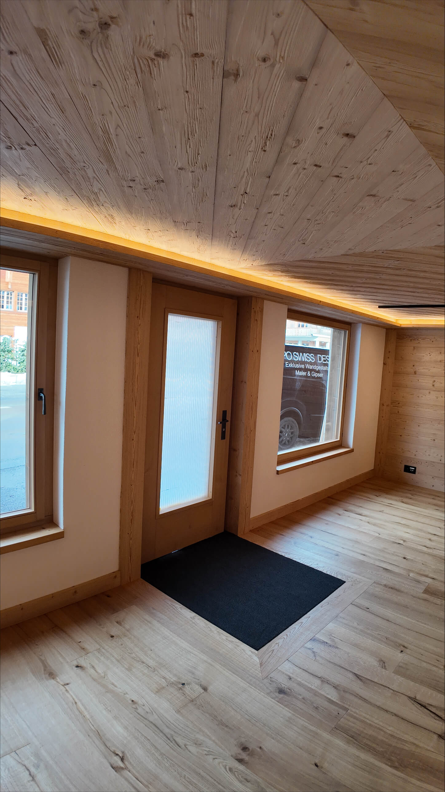 Leerer Raum mit dunkelblauen Wänden und Tür sowie Betonboden und weißer Decke.
