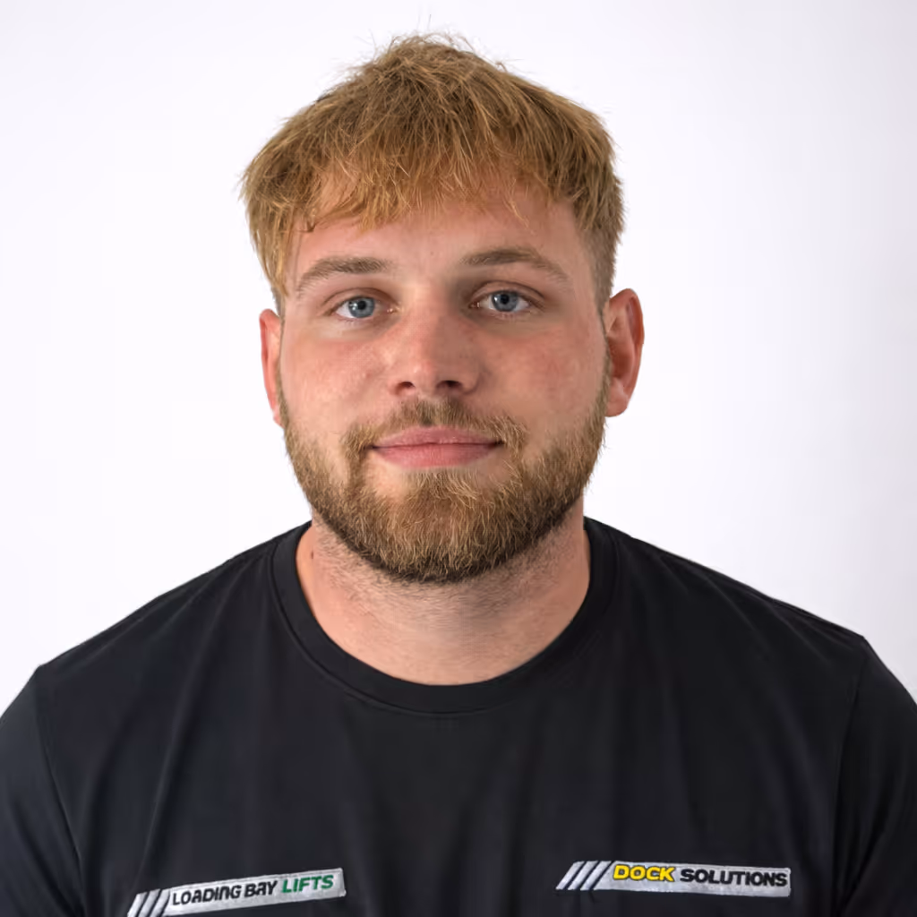Portrait of a man with light brown hair and beard wearing a black t-shirt that says Loading Bay Lifts and Dock Solutions on it, against a white background.