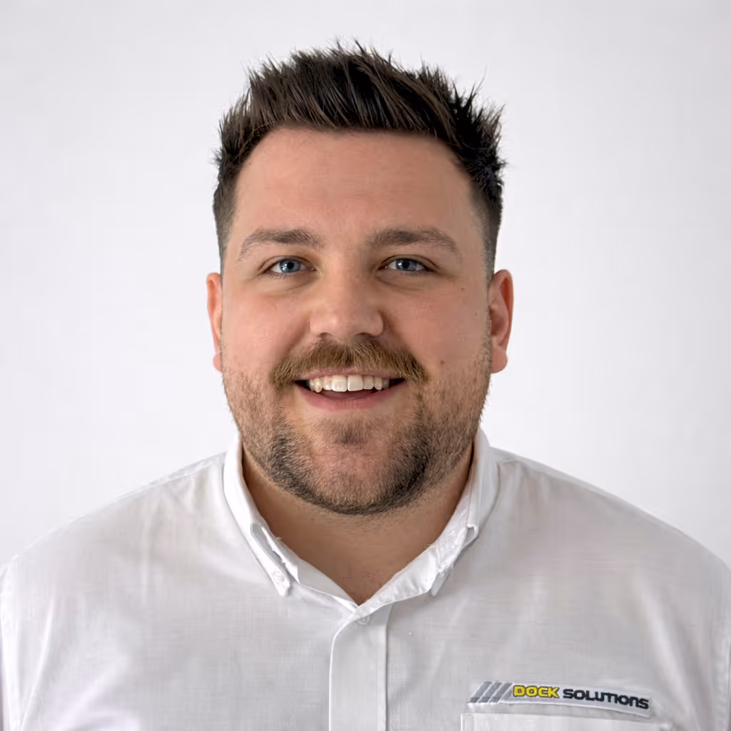 Man with short dark hair, light beard, and blue eyes smiling, wearing a white collared shirt with a 'Dock Solutions' logo on the pocket.