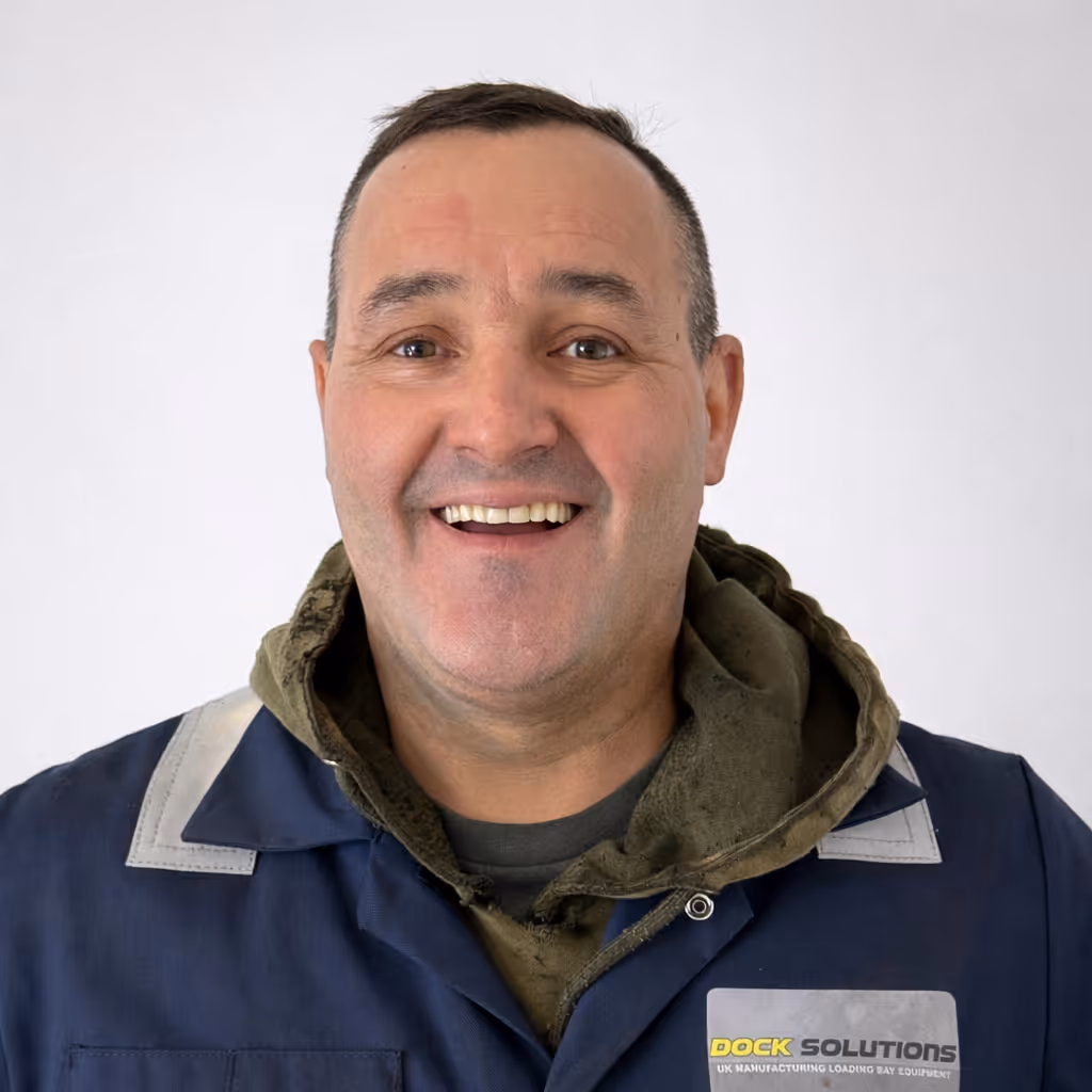 Smiling middle-aged man wearing a dark blue work jacket with a Dock Solutions logo, and a green hoodie underneath, against a plain white background.