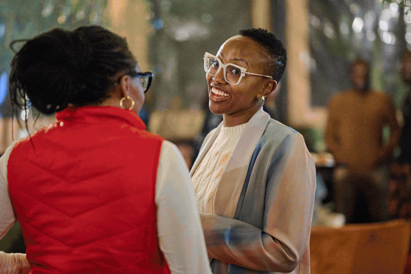 Three women seated closely together at a social event, looking at their smartphones and engaging with each other.