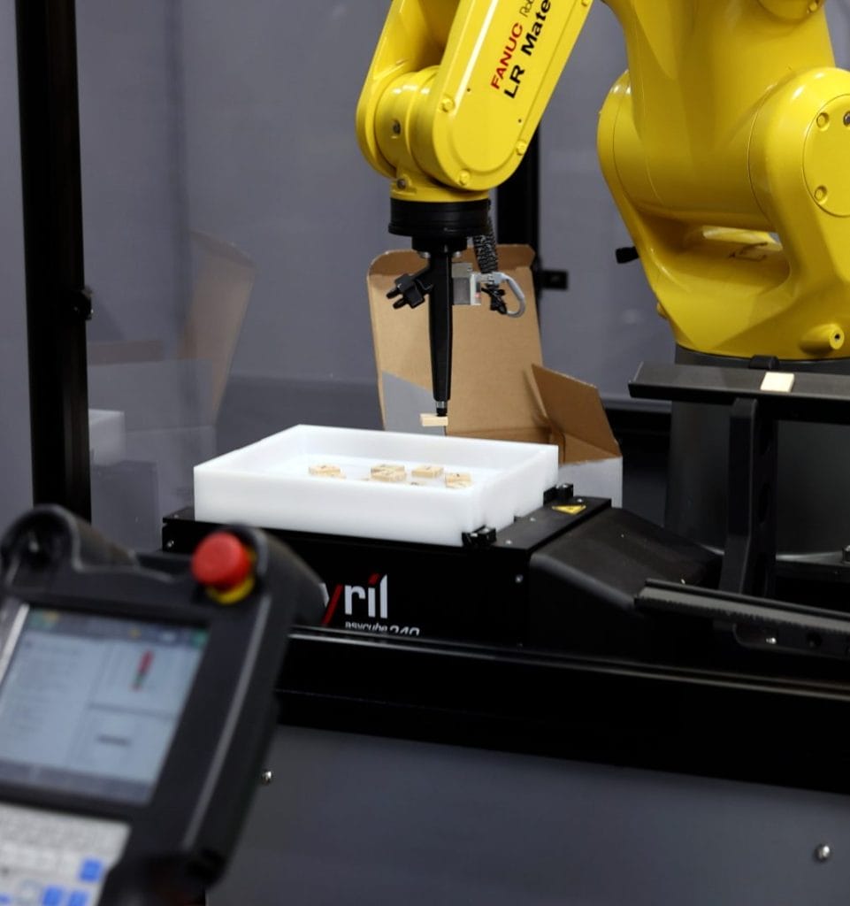 Image showing the robot's vacuum end effector holding a tile over the cube feeder