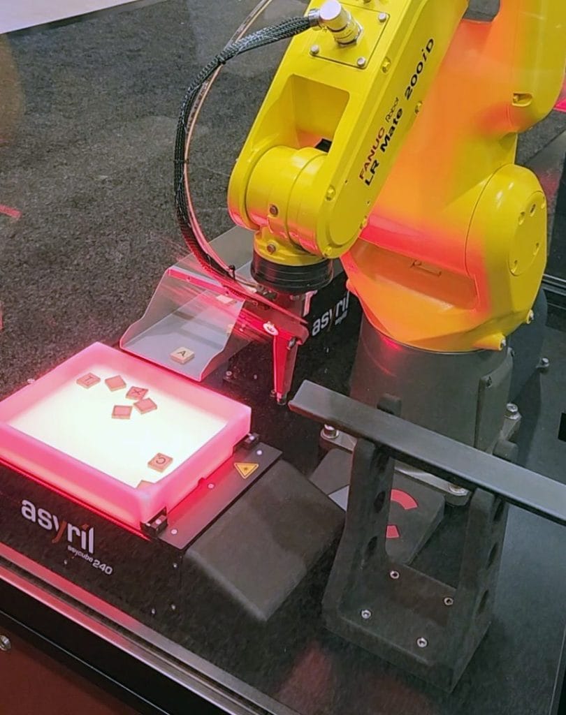 Image showing the backlit Asyril Ascube 240 feeder illuminated for the vision system camera imaging of the letter tiles