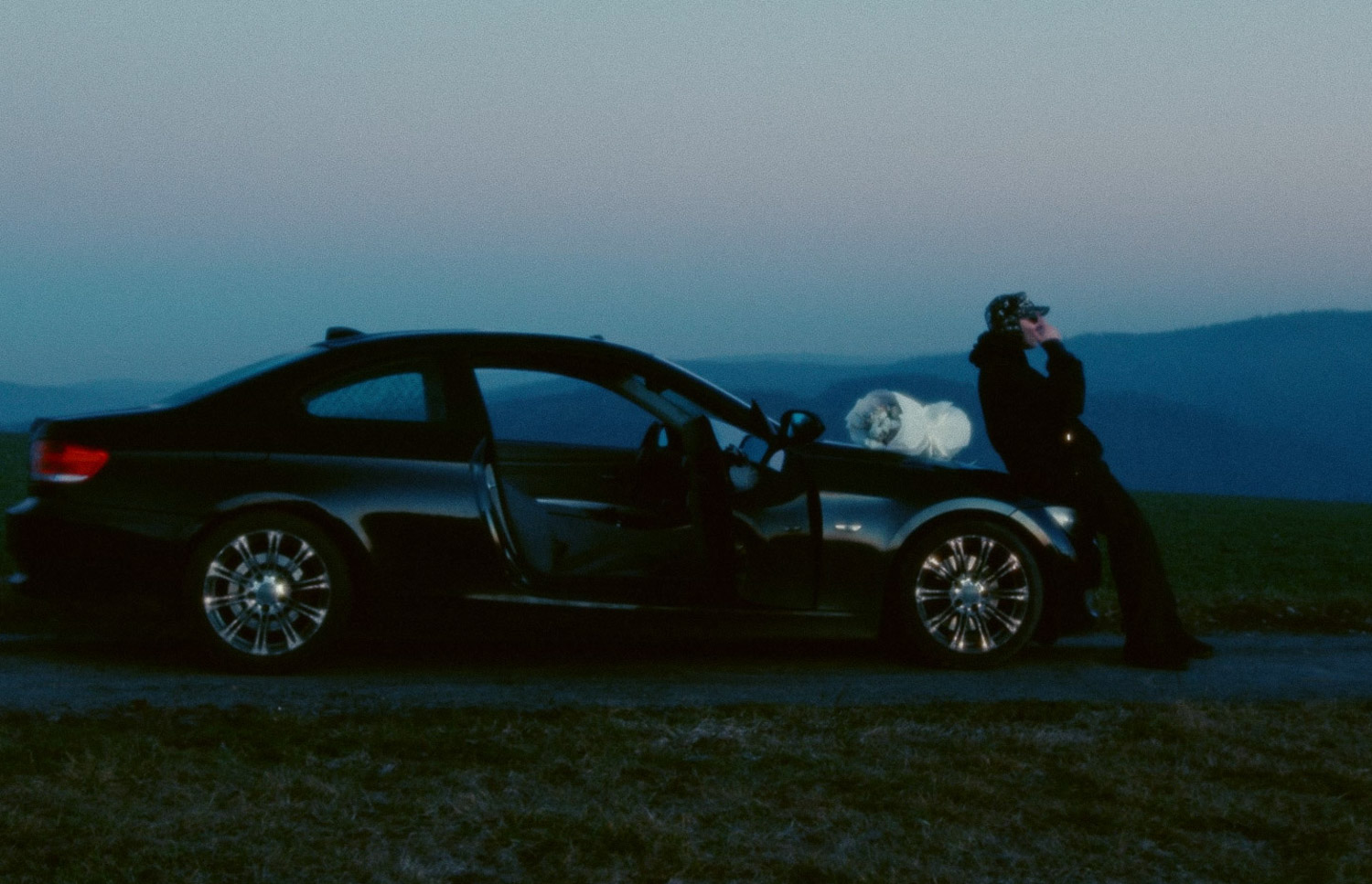 EXACT beside an open car at dusk