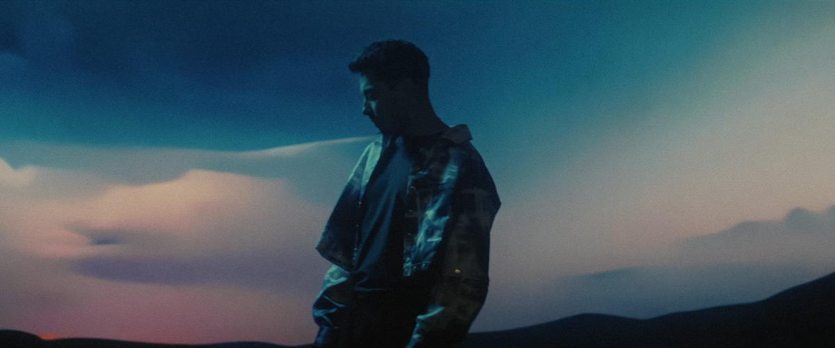 MIRAI performer against a blue projected landscape at dusk