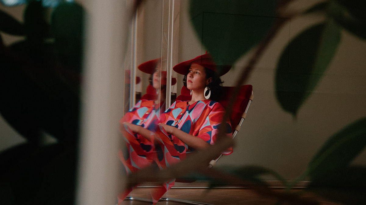 Models in red OP MAMA garments viewed through an interior doorway