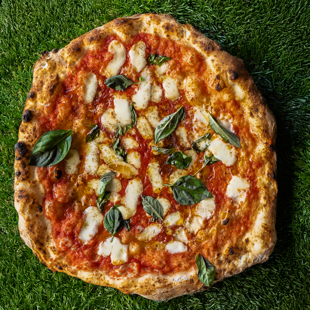 Pizza con salsa di pomodoro, mozzarella fusa, foglie di basilico e pepe nero su base di pasta croccante.