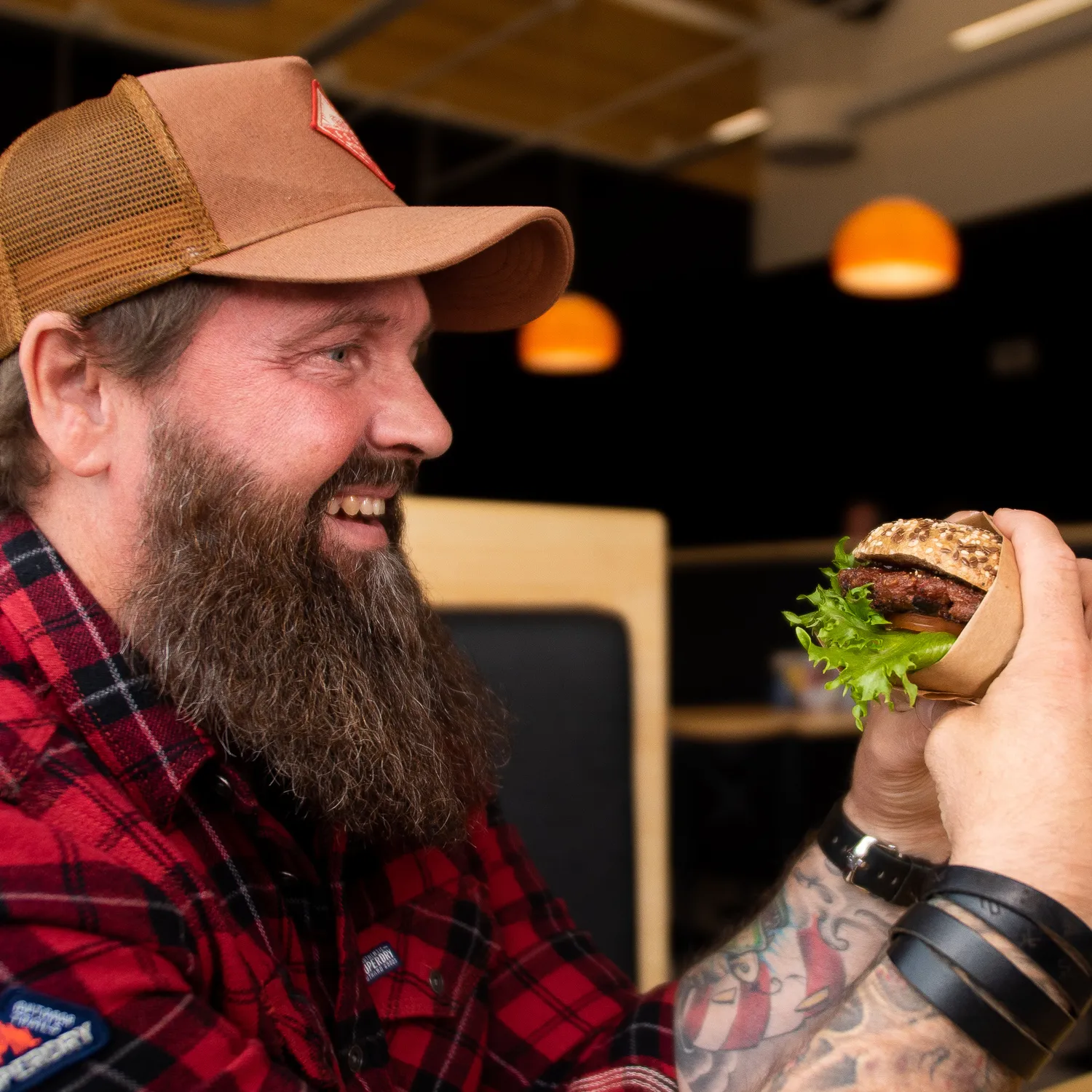 Kaksi naista istuu pöydän ääressä jakamassa friteerattuja naposteltavia ja hymyilee lämpimän riippuvalaisimen valossa.