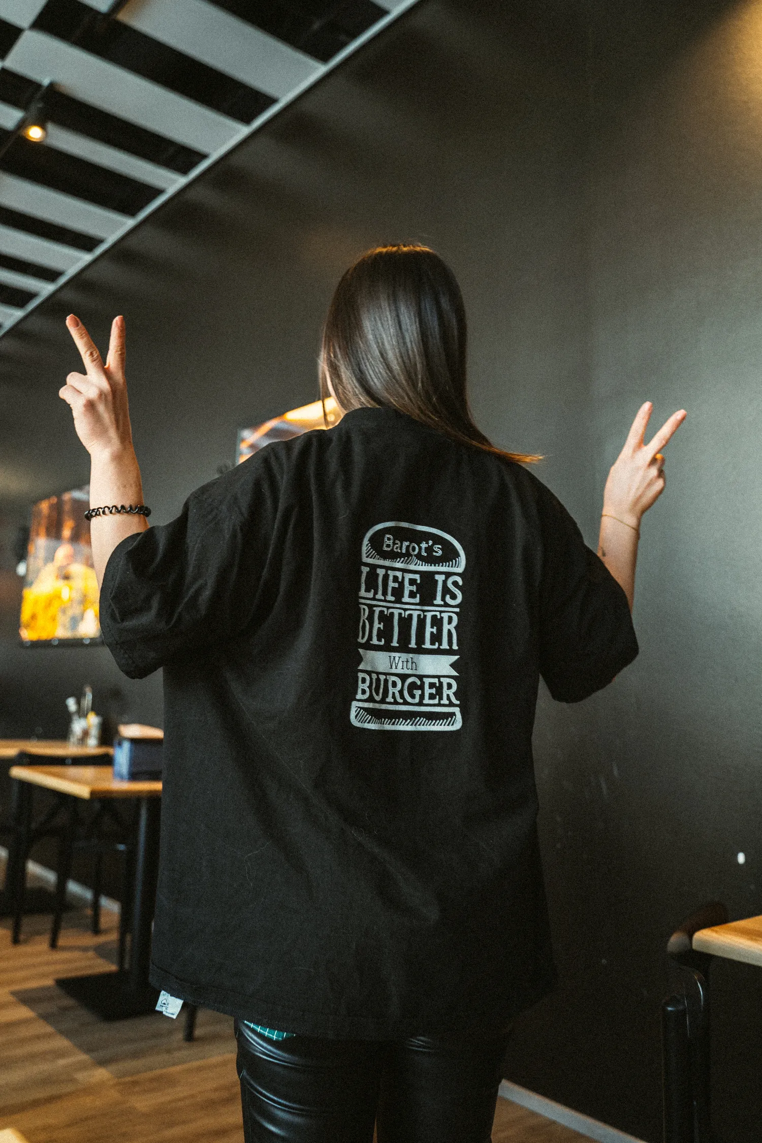 Kaksi naista istuu pöydän ääressä jakamassa friteerattuja naposteltavia ja hymyilee lämpimän riippuvalaisimen valossa.