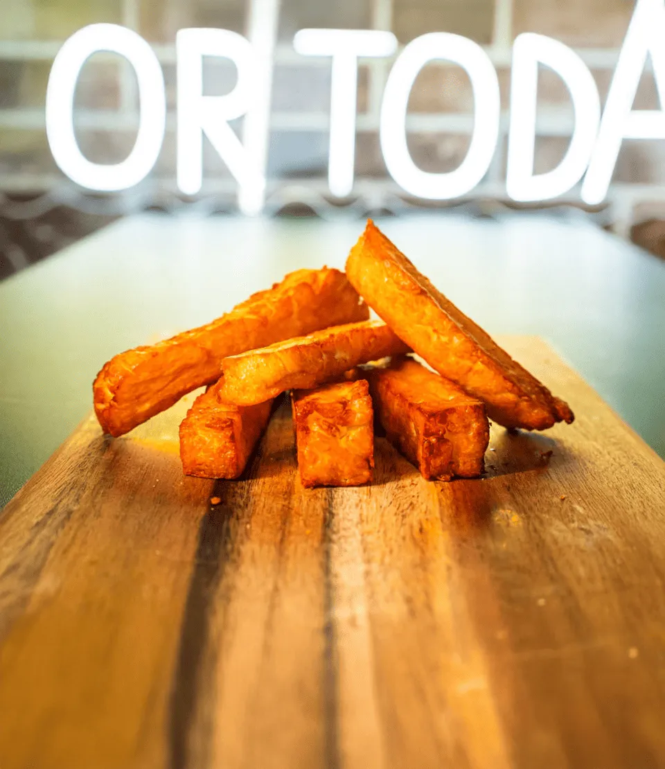 Kullanruskeat, rapeat halloumiperunat pinottuna puiselle laudalle.