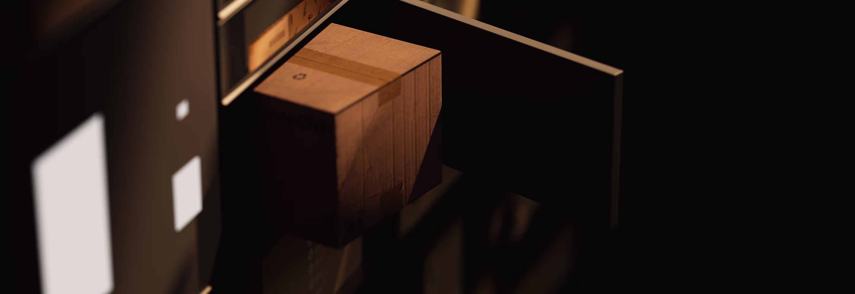 Ein braunes, mit Klebeband verschlossenes Paket auf einem Förderband in einem abgedunkelten Raum.