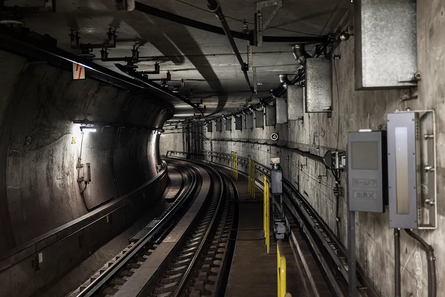 Curved subway tunnel with empty train tracks and dim lighting on concrete walls.