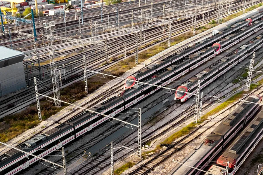 Aerial view of multiple high-speed trains parked on railway tracks in a rail yard with overhead power lines.