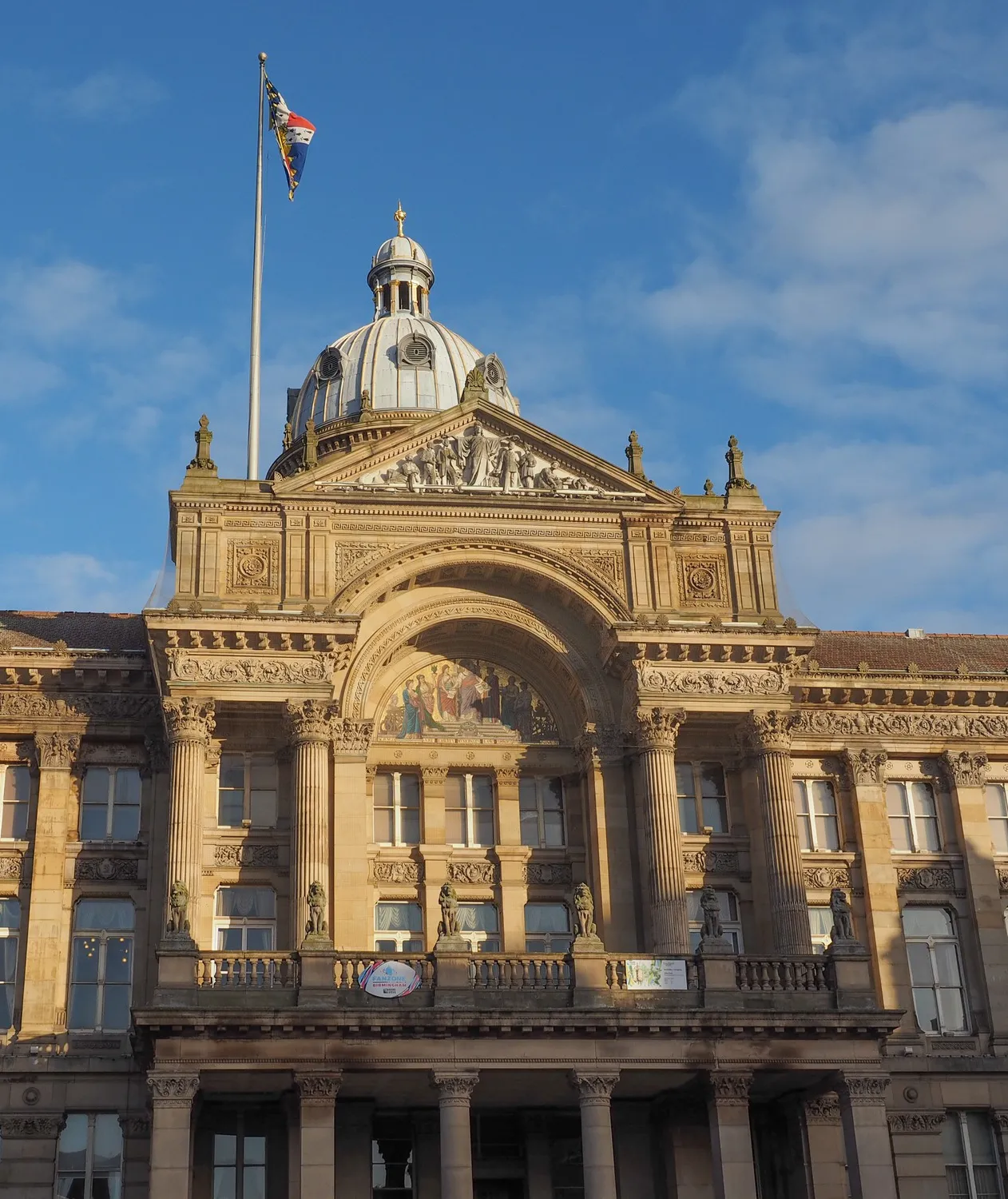 Close-up view of a classical stone building with columns and a large dome against a clear blue sky.