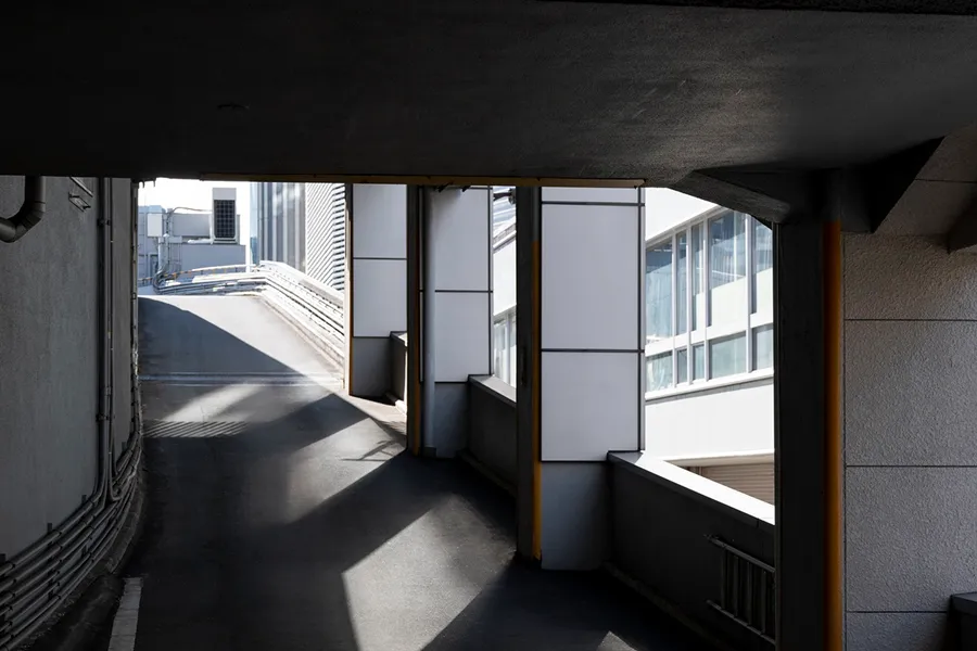 Sunlit ramp and walkway with modern building windows visible through large vertical openings.