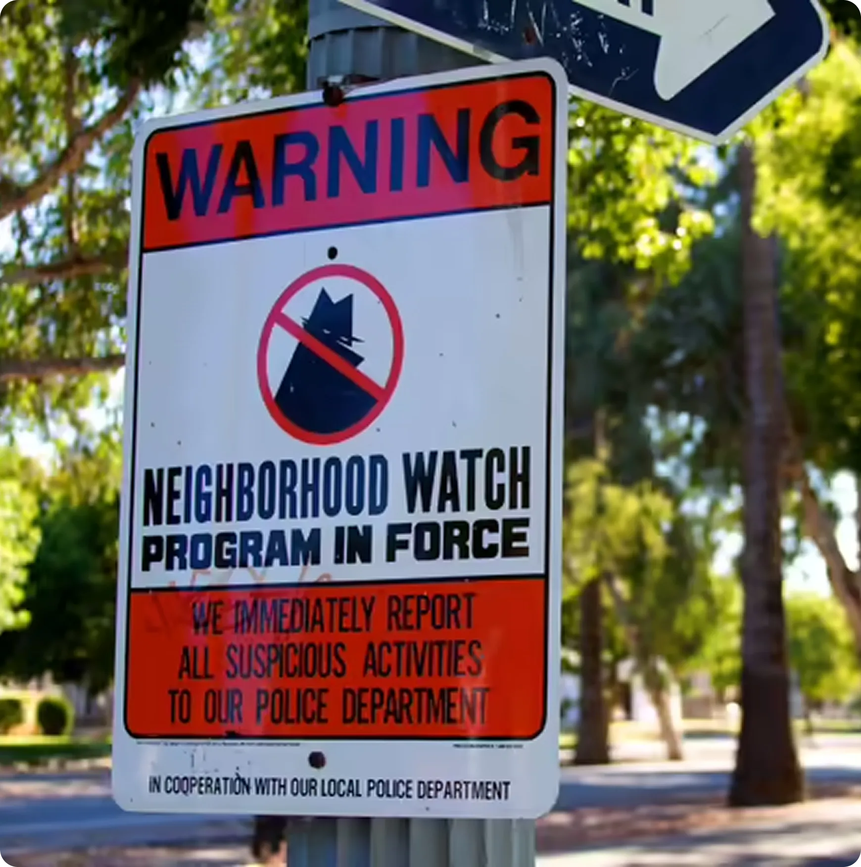 Neighborhood watch warning sign stating a program in force to report suspicious activities to the local police.