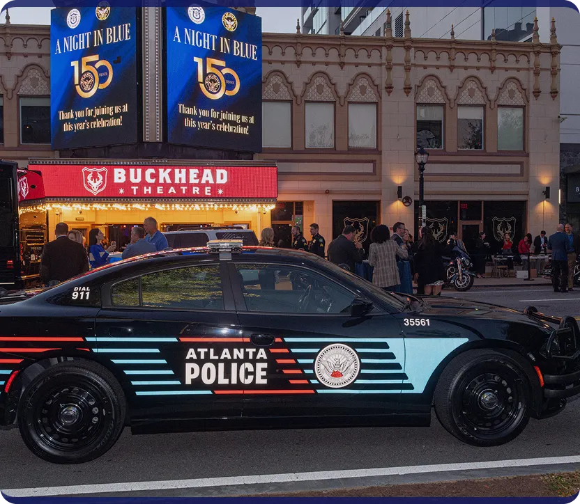 Black Atlanta Police car parked in front of Buckhead Theatre during an event at dusk.