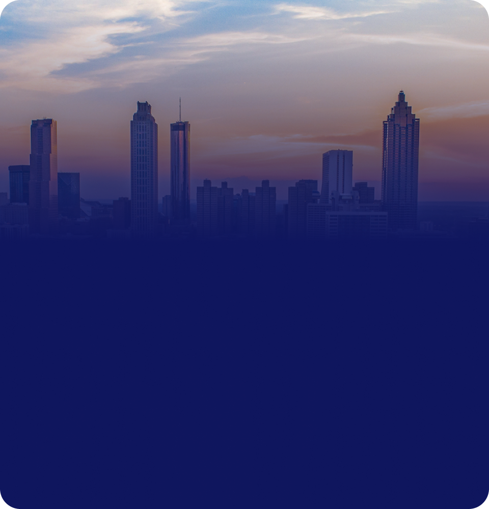 Aerial view of a modern city skyline at sunset with tall buildings and highways converging in the foreground.
