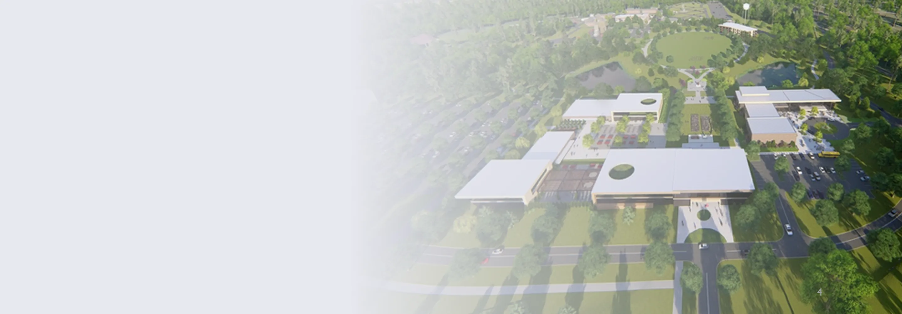Aerial view of a modern campus or facility with multiple white-roofed buildings, surrounding green spaces, parking lots, and roads.