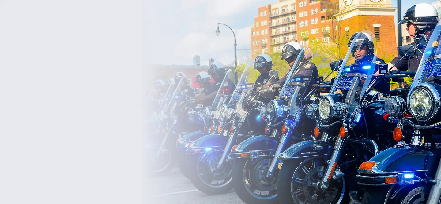 Line of police officers on motorcycles with flashing blue lights in an urban setting.