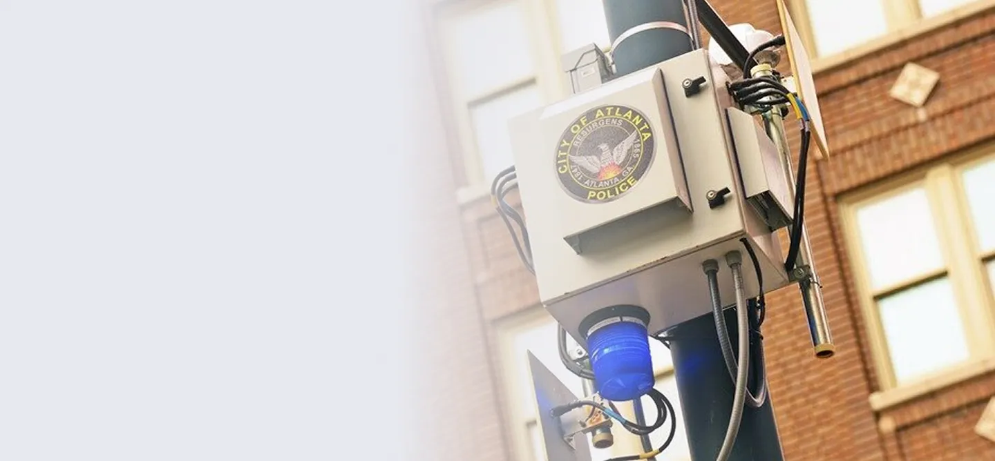 City of Atlanta Police surveillance camera and equipment mounted on a pole outside a brick building.