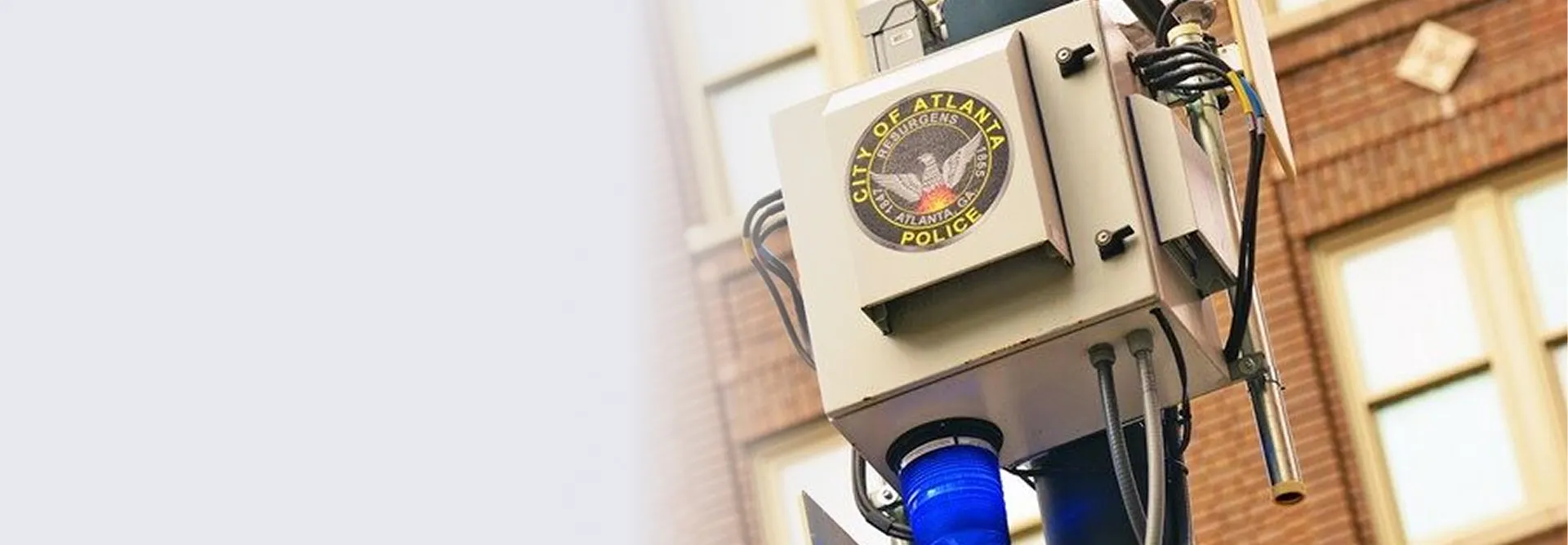 Close-up of a City of Atlanta Police surveillance or traffic camera mounted on a pole with a blue light beneath it.