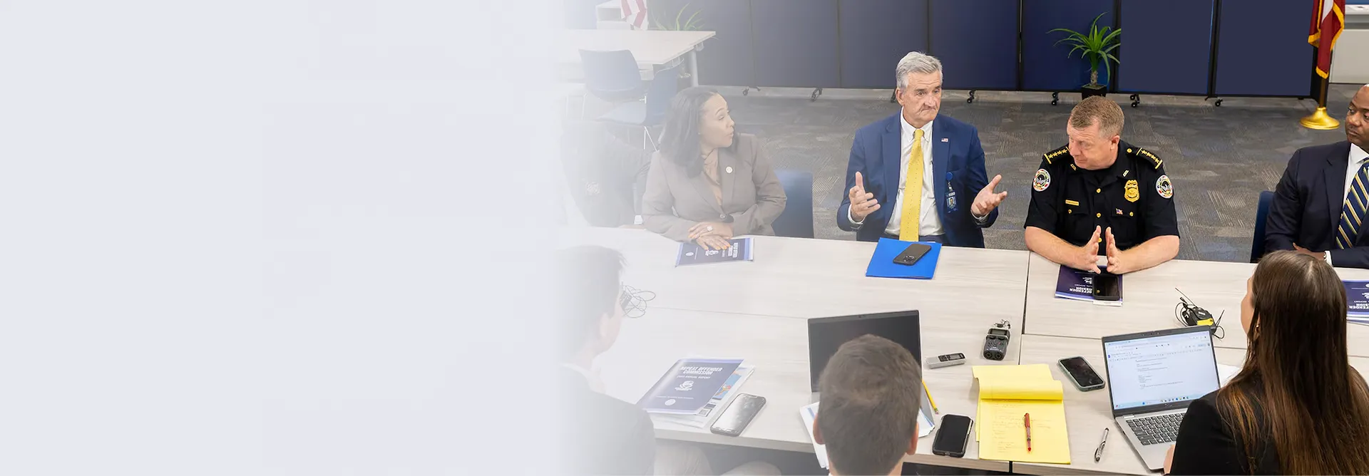 Group of professionals, including a man in a police uniform, seated around a table during a discussion or meeting.