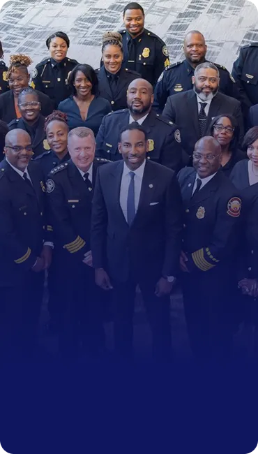 Group portrait of diverse police and fire department officers in uniform standing together indoors.