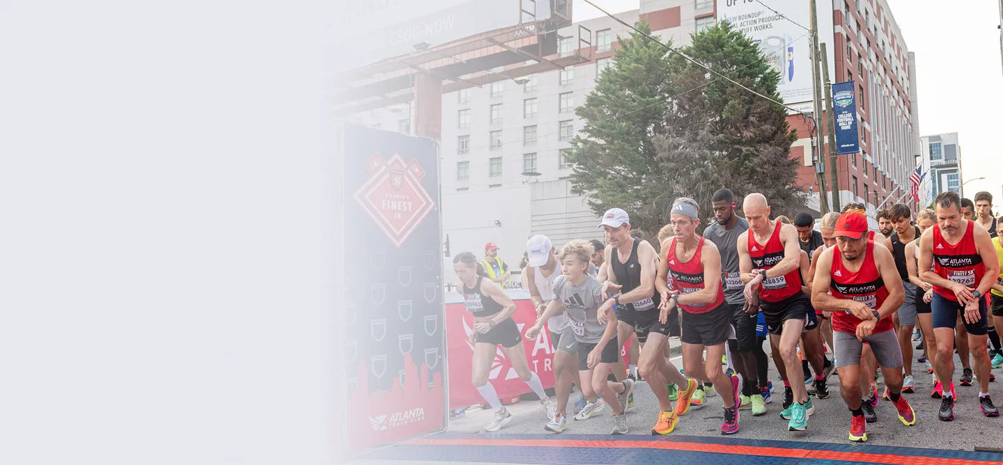 Group of runners at the start line of Atlanta's Finest 5K race in an urban setting.