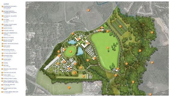 Detailed site plan showing various designated zones including leadership building, auditorium, office and flexible buildings, housing, training, visitor station, vehicle staging, picnic areas, and expanded trail systems surrounded by wooded areas and open fields.