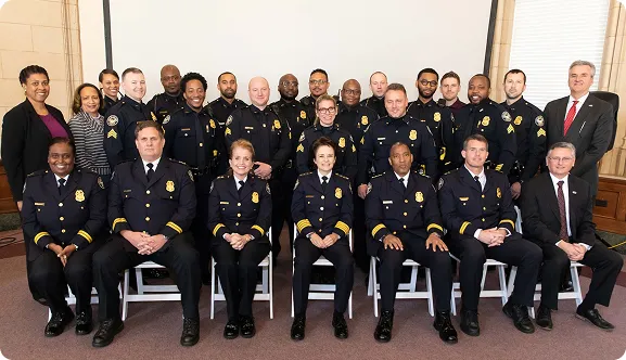 Group photo of diverse police officers and officials in uniform and suits posing indoors.