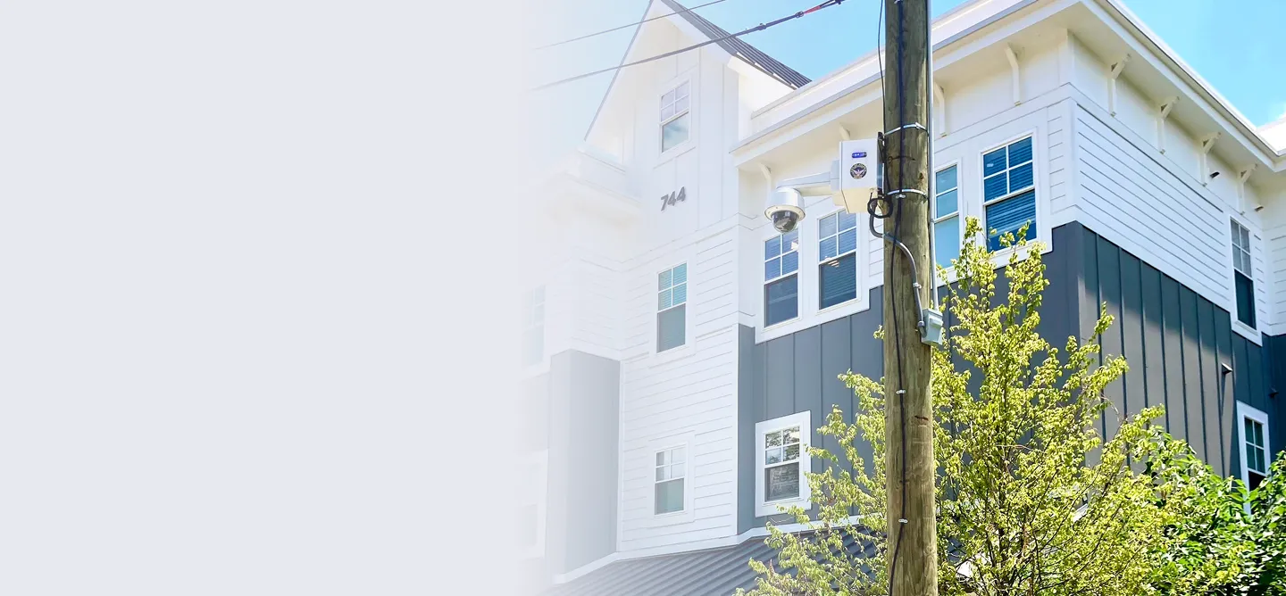 Exterior of a modern, three-story apartment building with gray and white siding and multiple windows under clear blue sky.