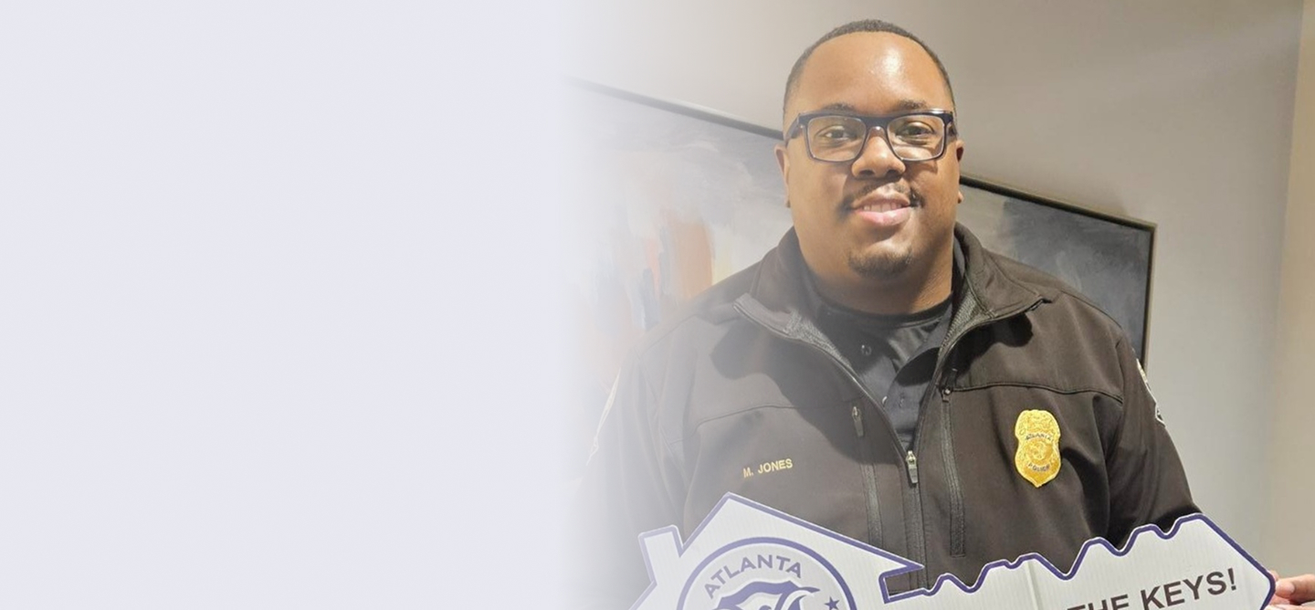 Smiling police officer in uniform holding a large cutout shaped like a key with the Atlanta Police logo.