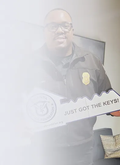Man in a security or official jacket holding a large key-shaped sign that says 'JUST GOT THE KEYS!'