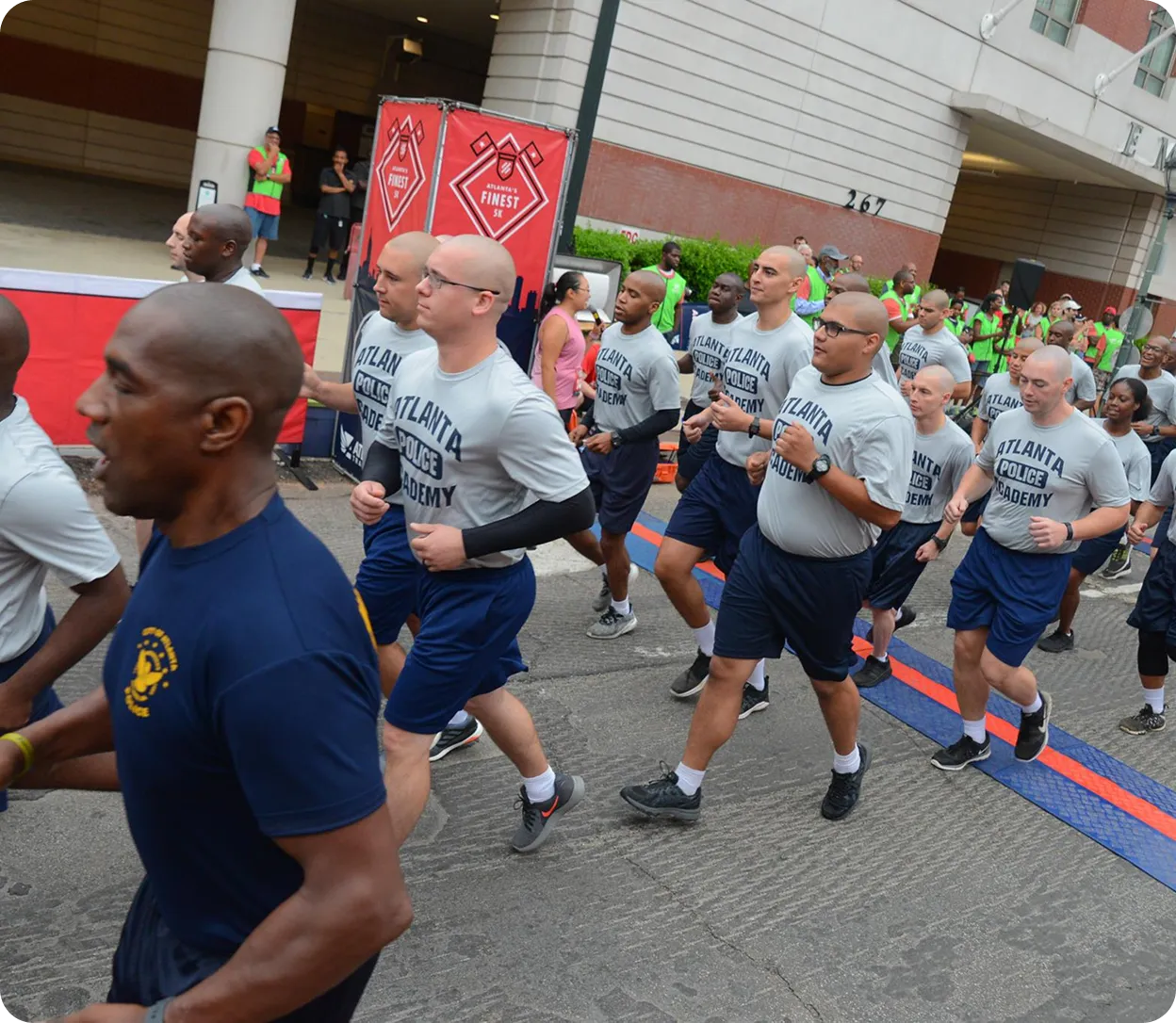 Group of Atlanta Police Academy cadets jogging in formation during an outdoor event.