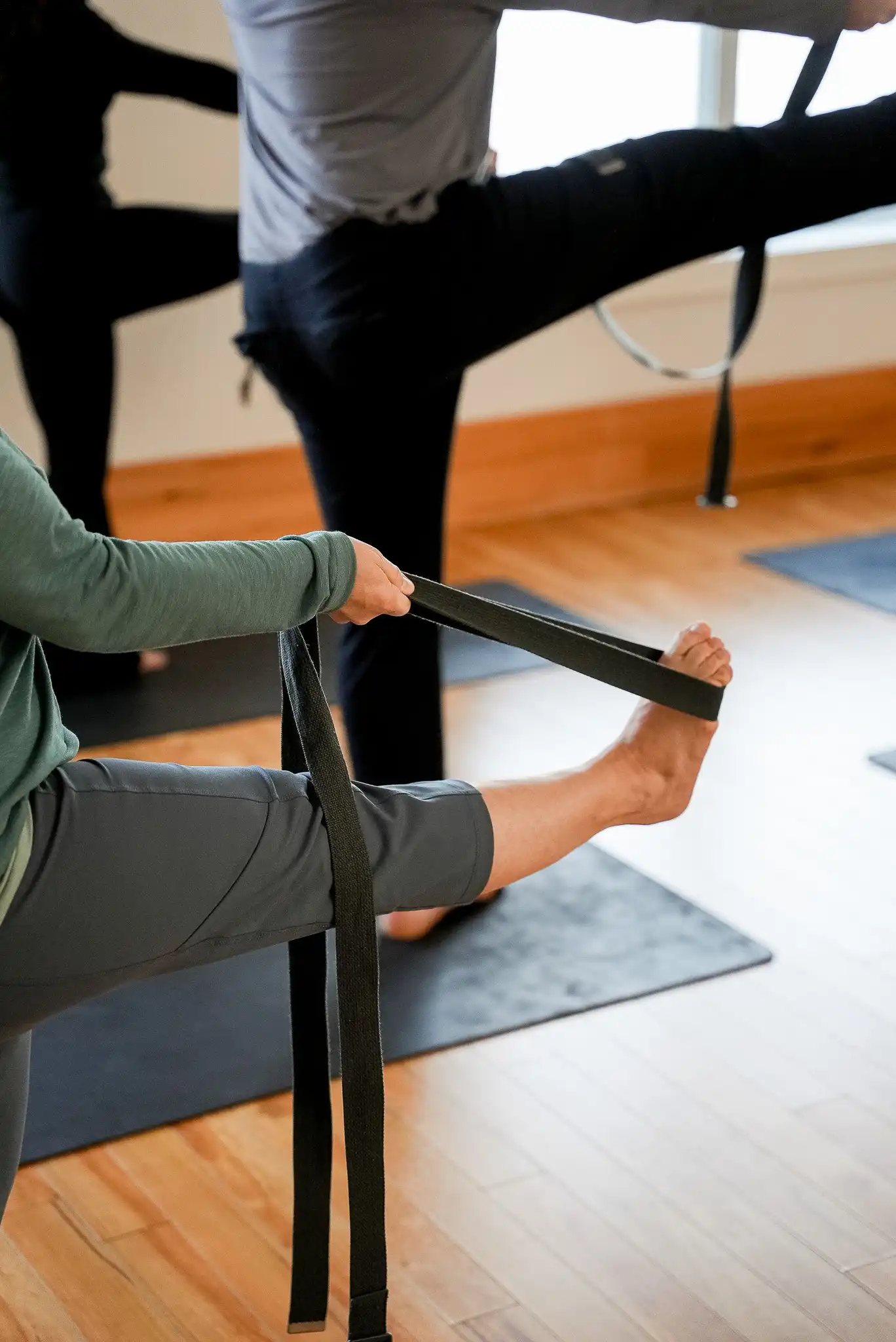 Séance de yoga doux et stretching au studio KŌR, posture d'étirement en douceur sur tapis.