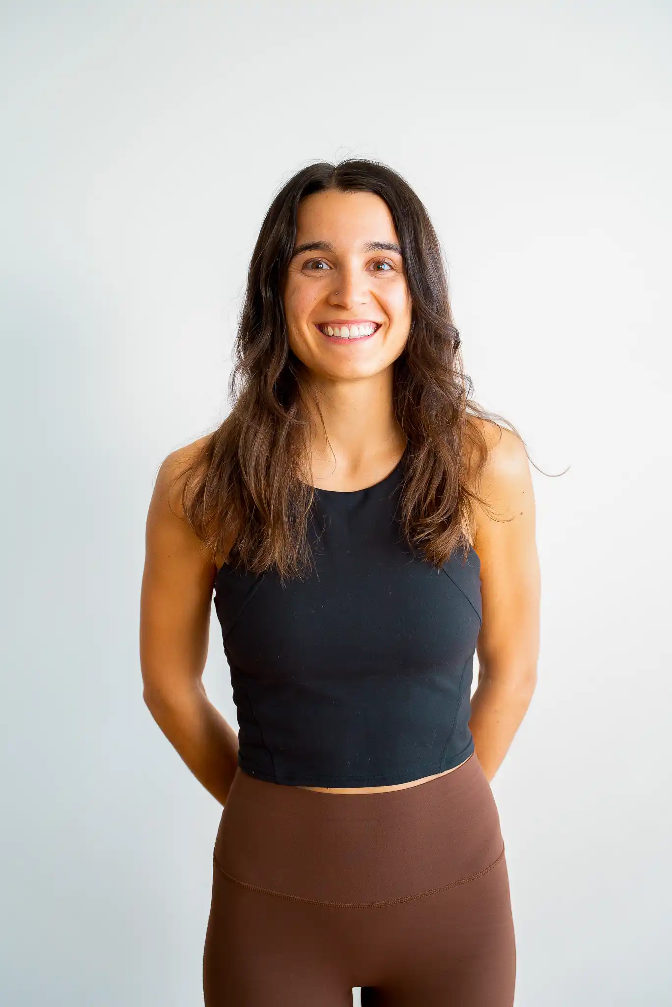 Ann-Marie, professeure de Yoga Flow au Studio KŌR, portrait souriant en débardeur noir sur fond clair.
