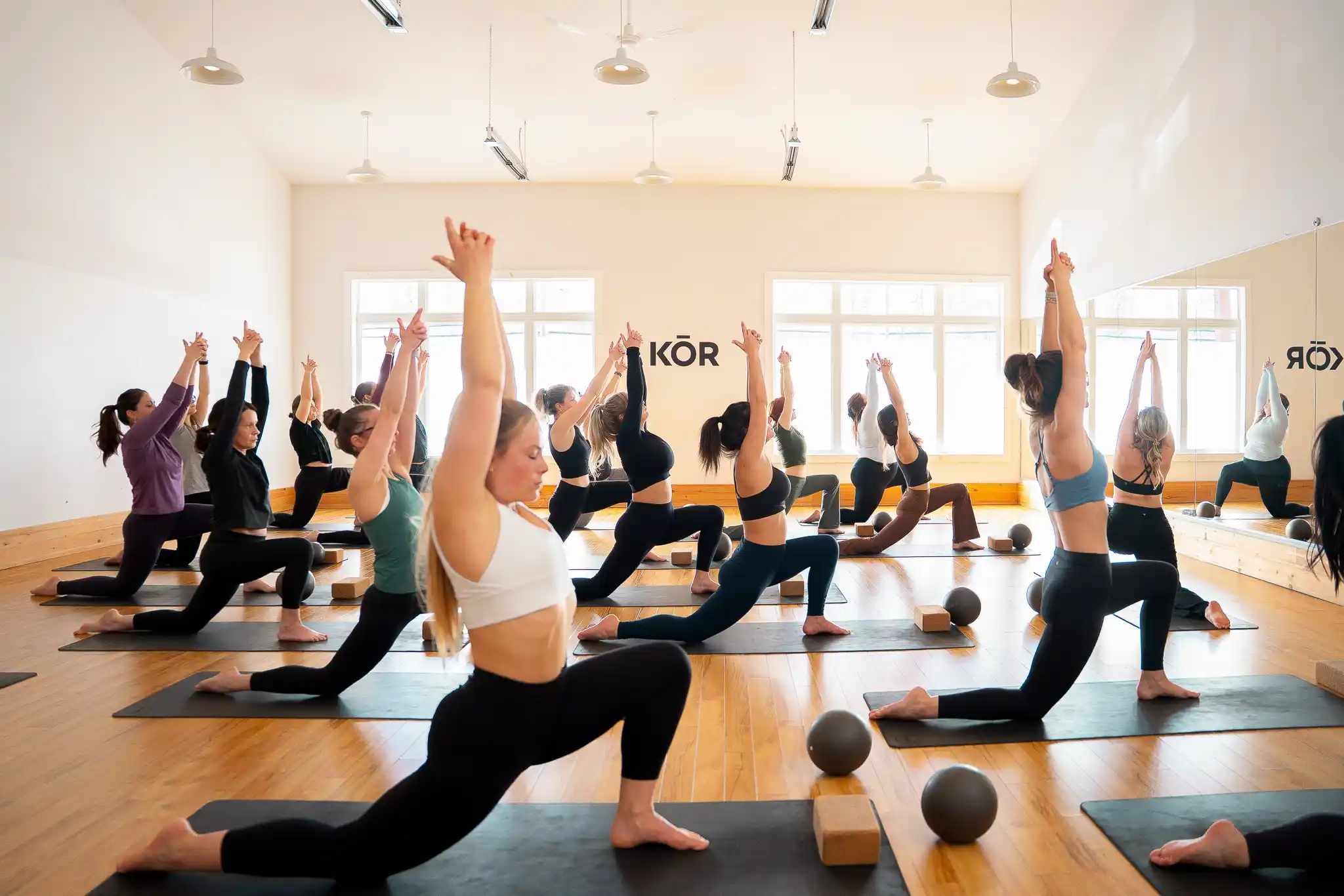 Cours de Hot Yoga au studio KŌR Bromont, pratique dynamique dans une salle chauffée.