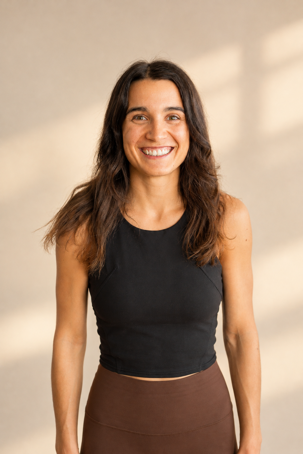 Ann-Marie, professeure de Yoga Flow au Studio KŌR, portrait souriant en débardeur noir sur fond clair.