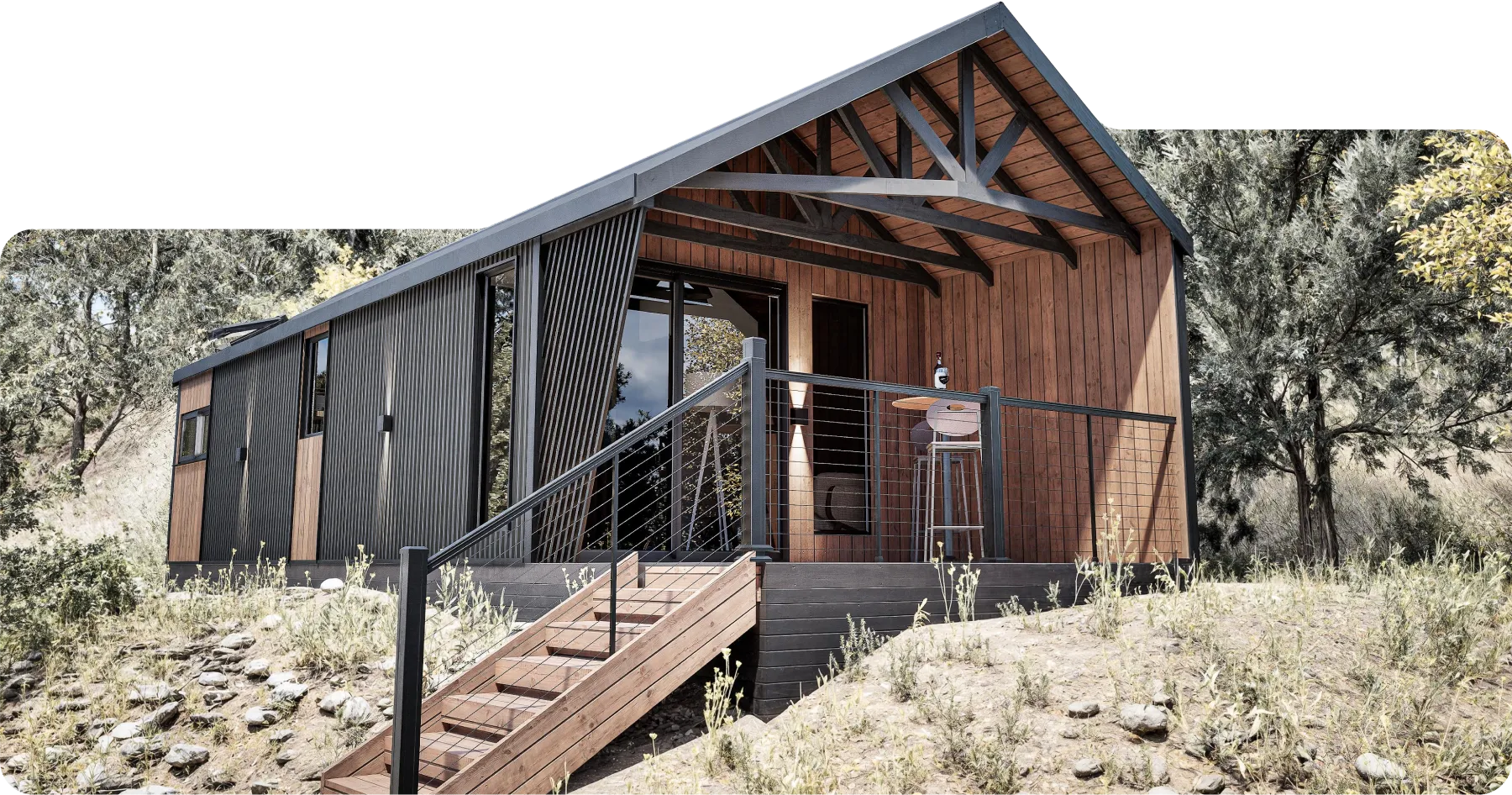 Modern cabin model Cliff, with wood and black metal siding, featuring a porch with metal railing, stool, and table, surrounded by trees and dry grass.