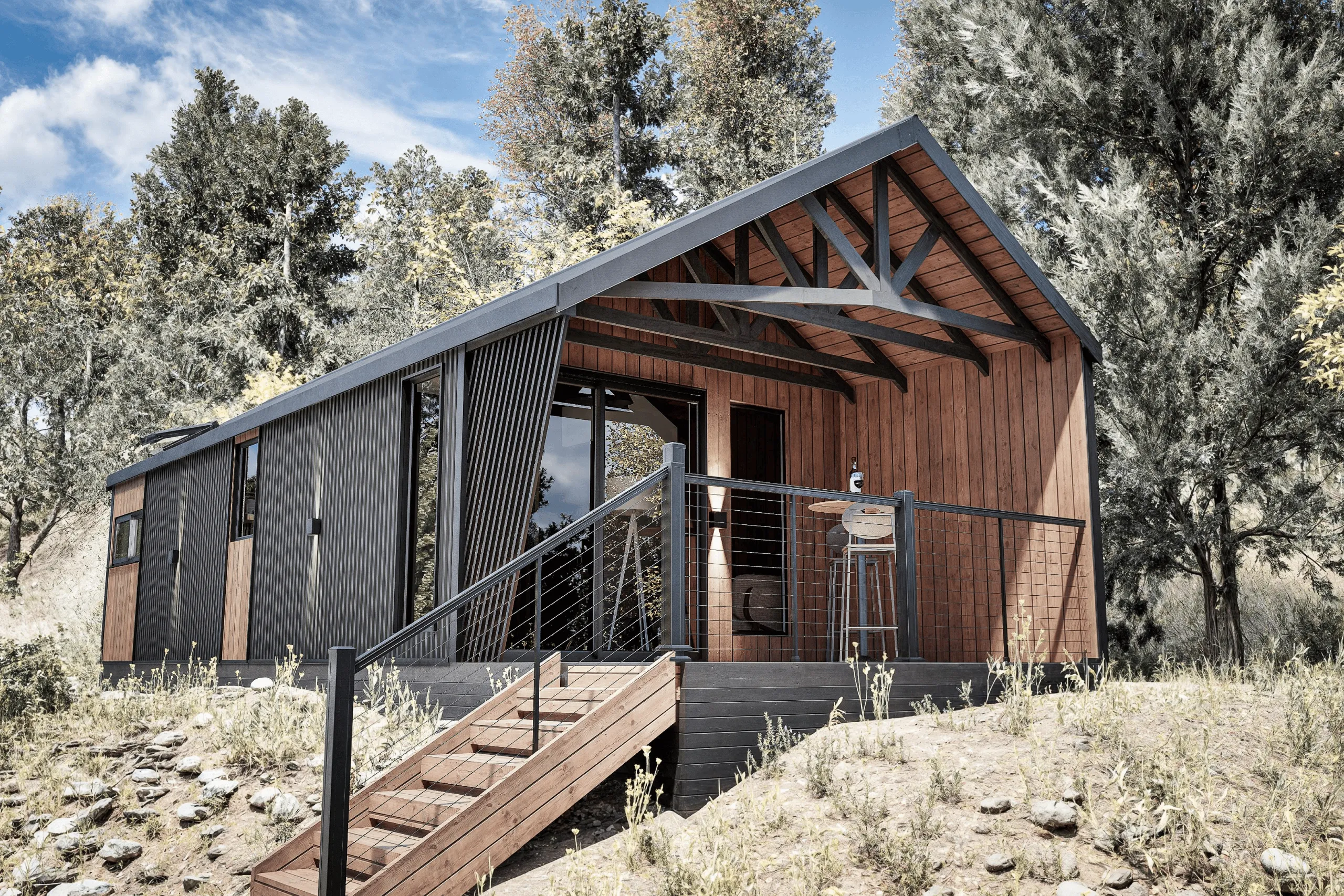 The cliff model cabin with black metal and wood siding featuring an elevated porch with a wooden table, stool, and a bottle, surrounded by trees and grassy terrain.