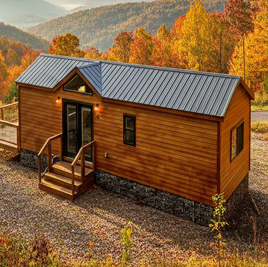 The Forest Glen model with a metal roof surrounded by autumn trees on a mountainside.