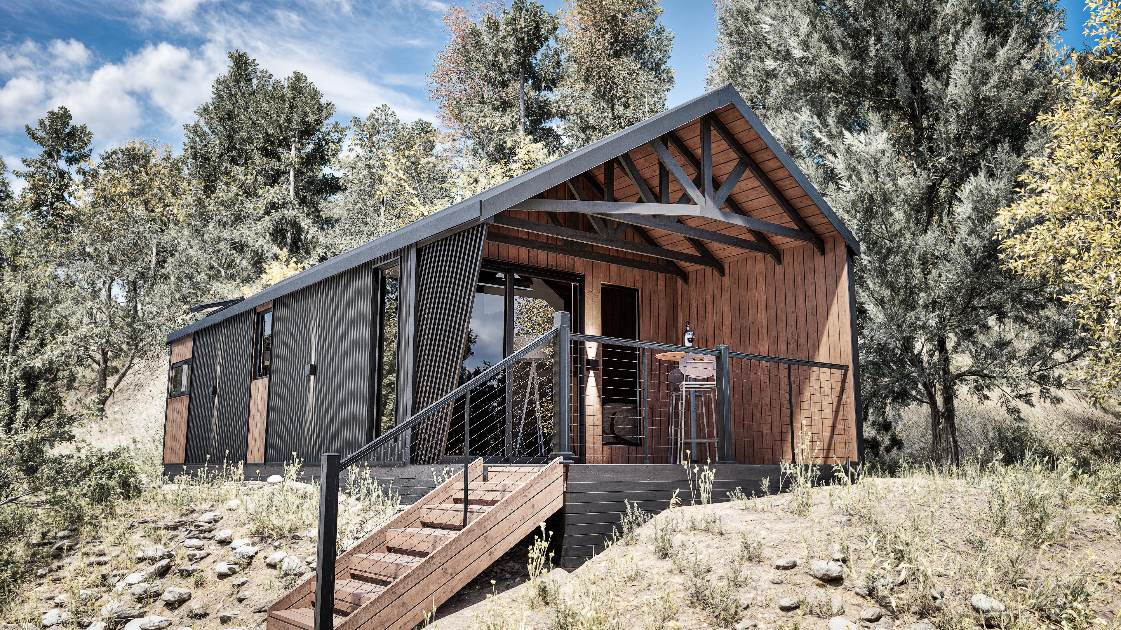 Modern cabin with wooden and black exterior, raised on a slope with stairs leading to a small porch.