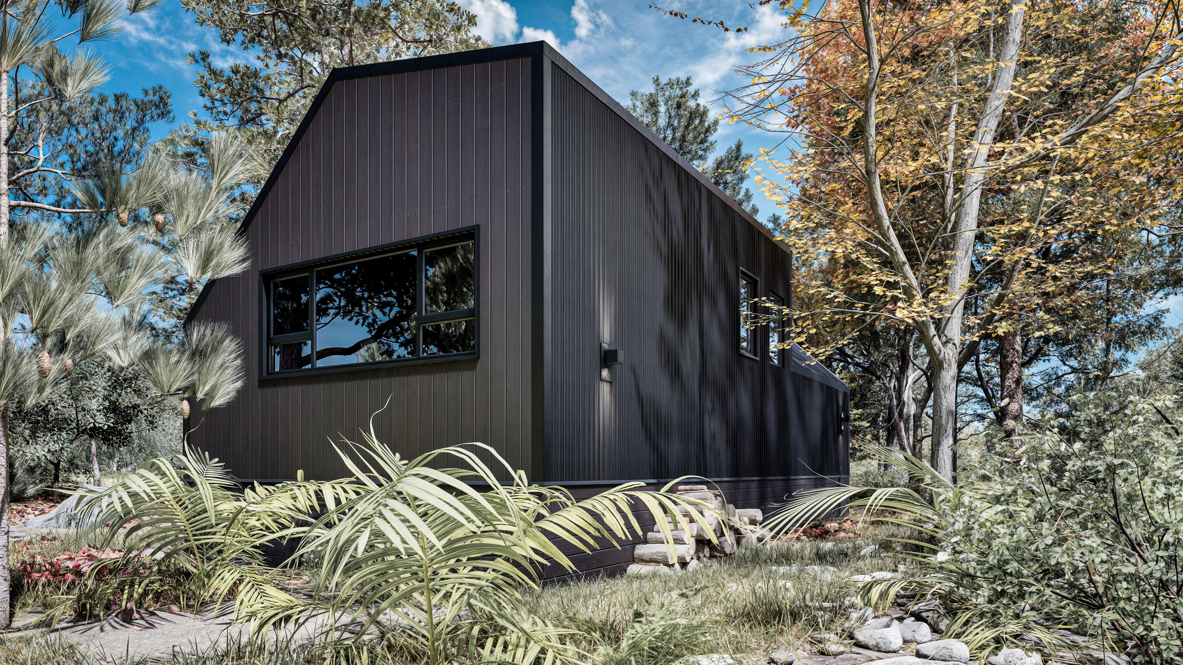 A modern, dark-colored cabin with large windows is surrounded by trees and foliage under a partly cloudy sky.