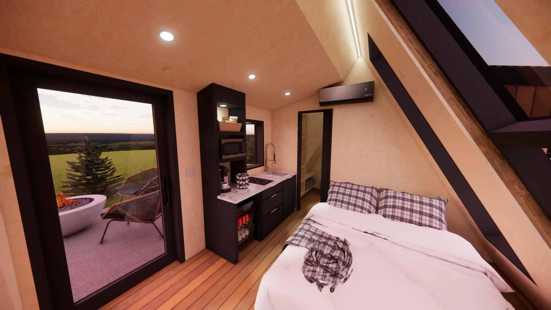 A small modern cabin interior with a kitchenette, bed, and door to an outdoor patio with chairs and a fire pit.