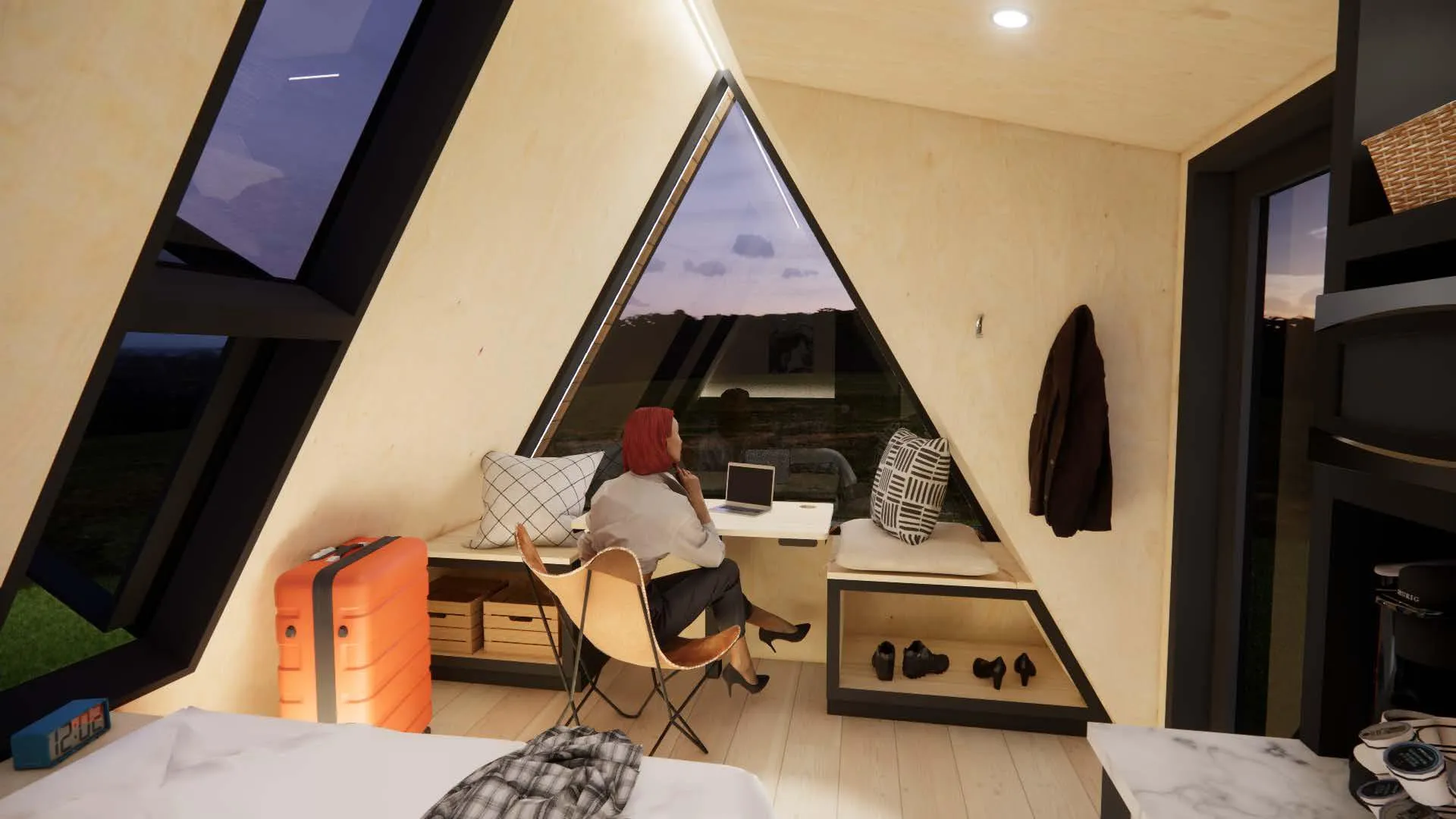 A person sits at a desk with a laptop in a modern, A-frame cabin with large windows.