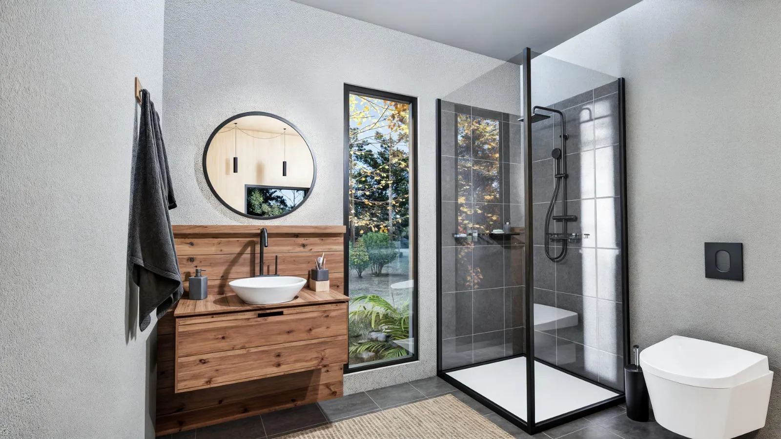 Modern bathroom with a wooden vanity, round mirror, vessel sink, glass-enclosed shower, large window, and wall-mounted toilet.