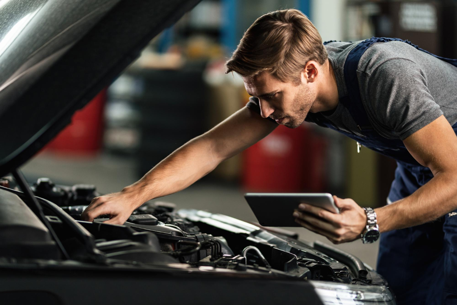 Automotive technician using a diagnostic scanner on an engine