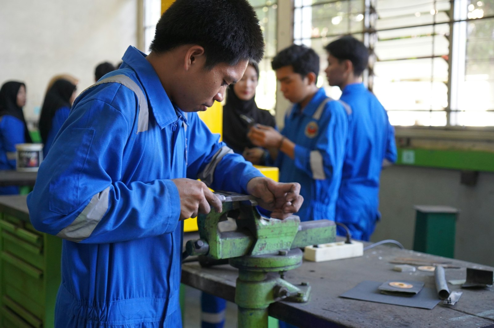 An apprentice operating a machine in a factory workshop